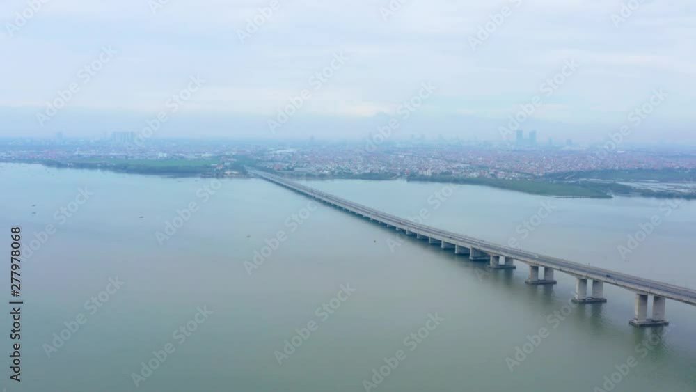 Aerial view of Suramadu bridge with Madura strait background and Surabaya city on misty morning. Shot in 4k resolution from a drone flying forwards Aerial view of Suramadu bridge with Madura strait background and Surabaya city on misty morning. Shot in 4k resolution from a drone flying forwards