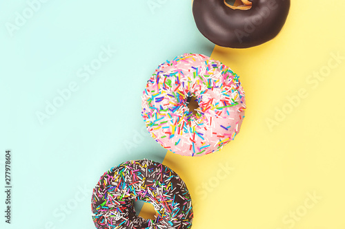 Three tasty doughnuts on turquoise background.