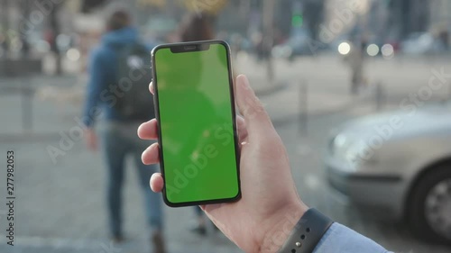 Wallpaper Mural NEW YORK - April 5, 2018: Young man hands holding a smartphone with vertical green screen background car city touchscreen wireless business evening cellphone communication device digital internet Torontodigital.ca
