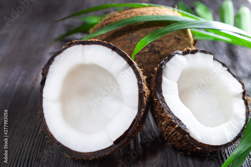 Ripe whole and half cut coconut on wooden background.