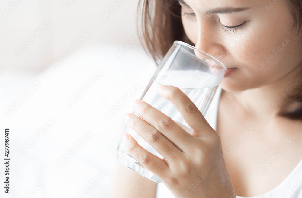 Close up woman drinking pure water from glass with light in the morning, Selective focus Close up woman drinking pure water from glass with light in the morning, Selective focus