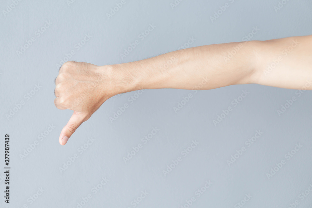 Man hand thumb down sign on grey background Man hand thumb down sign on grey background