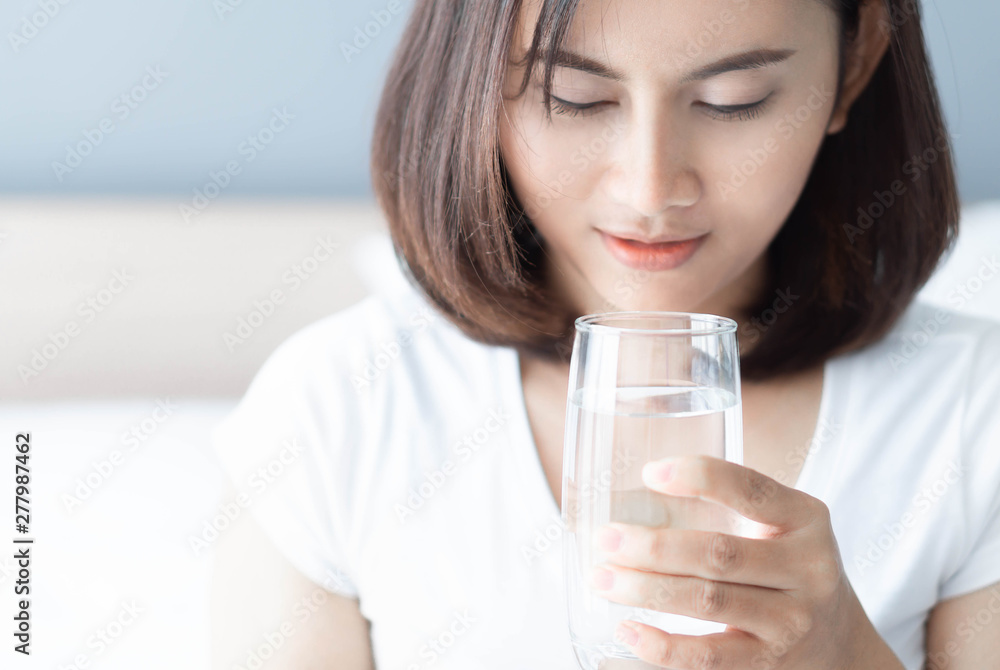 Close up woman drinking pure water from glass with light in the morning, Selective focus Close up woman drinking pure water from glass with light in the morning, Selective focus