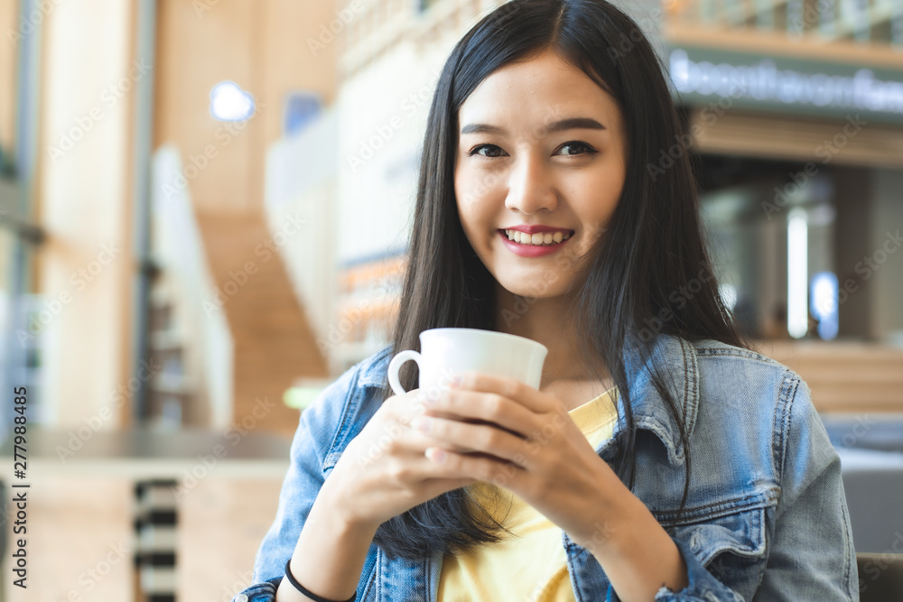 Asian woman in a cafe drinking coffee .Portrait of Asian woman smiling in coffee shop cafe vintage colour tone. Asian woman in a cafe drinking coffee .Portrait of Asian woman smiling in coffee shop cafe vintage colour tone.