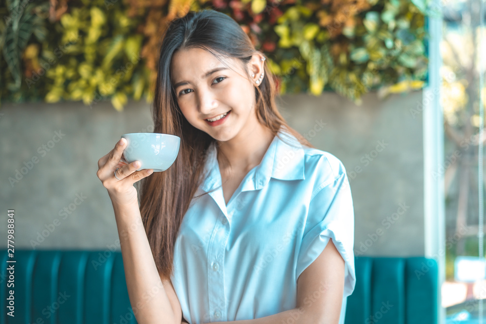 Asian woman in a cafe drinking coffee .Portrait of Asian woman smiling in coffee shop cafe vintage colour tone. Asian woman in a cafe drinking coffee .Portrait of Asian woman smiling in coffee shop cafe vintage colour tone.