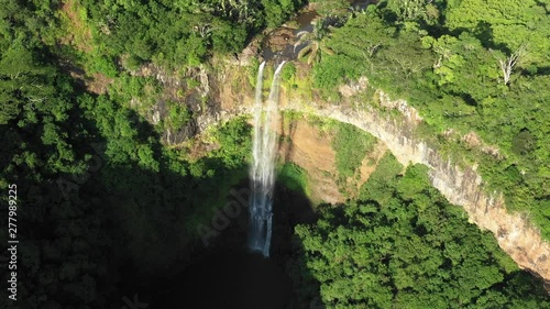  Aerial view of the amazing wonderful waterfall on the Mauritius island surrounded by tropical bushes and trees on a hot warm day. The concept of rest in natural reserves. 