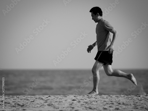 Motion blur Asian man running on the beach in evening, lifestyle concept. Black and white.