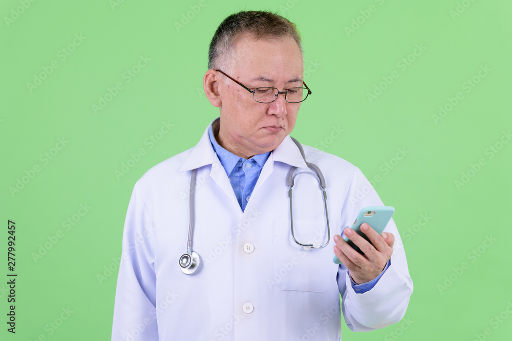 Mature Japanese man doctor with eyeglasses using phone Mature Japanese man doctor with eyeglasses using phone