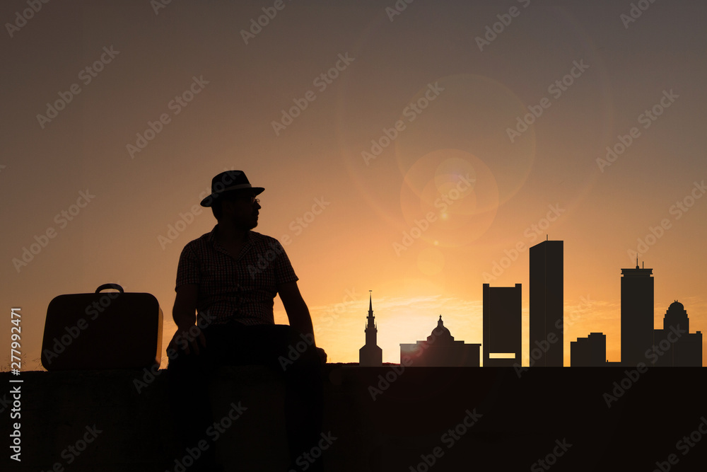 Traveler with suitcase and hat in front of boston city skyline in united states