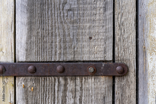 metal plank on an old wooden door. The metal level fastens wooden slats. Old wooden door with a metal bracket.
