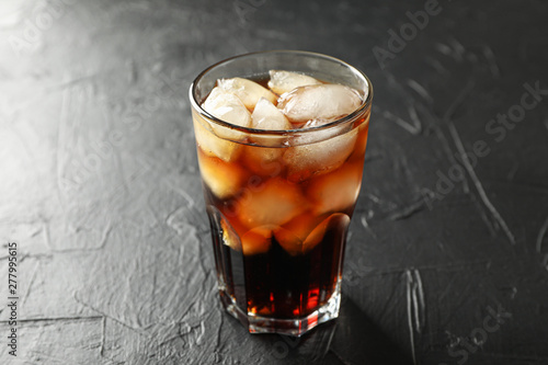 Glass of cold cola on black cement background