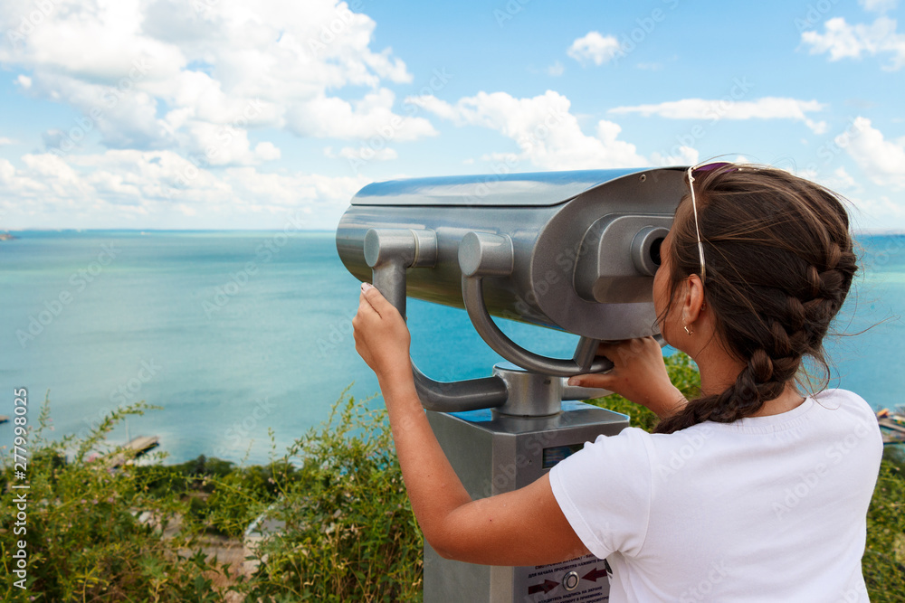 Obraz premium girl on vacation looking through a binocular at the seascape