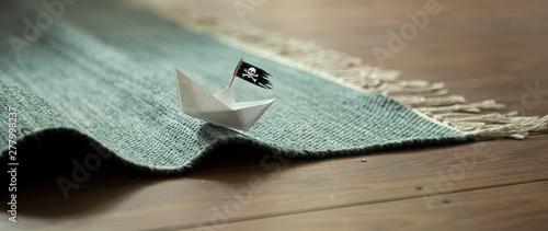 Fotografi Paper Boat with Jolly Roger on Carpet Waves
