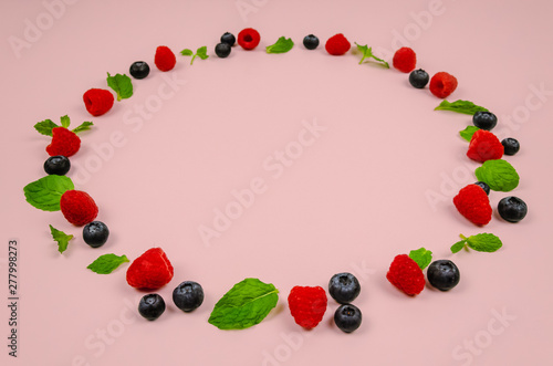 Fresh blueberries, raspberries and mint leaf on top view with pastel pink color background for healthy food concept.