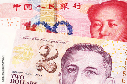 A close up image of a red, one hundred yuan bank note from the People's republic of China, in macro with a two dollar bill from Singapore
