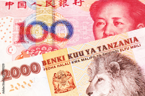 An orange and white two thousand Tanzanian shilling note with a red Chinese, one hundred yuan renminbi note in macro