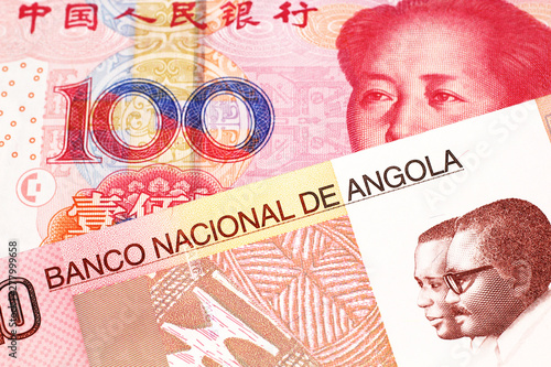 A colorful ten kwanza bill from Angola with a red, Chinese 100 yuan bank note close up in macro