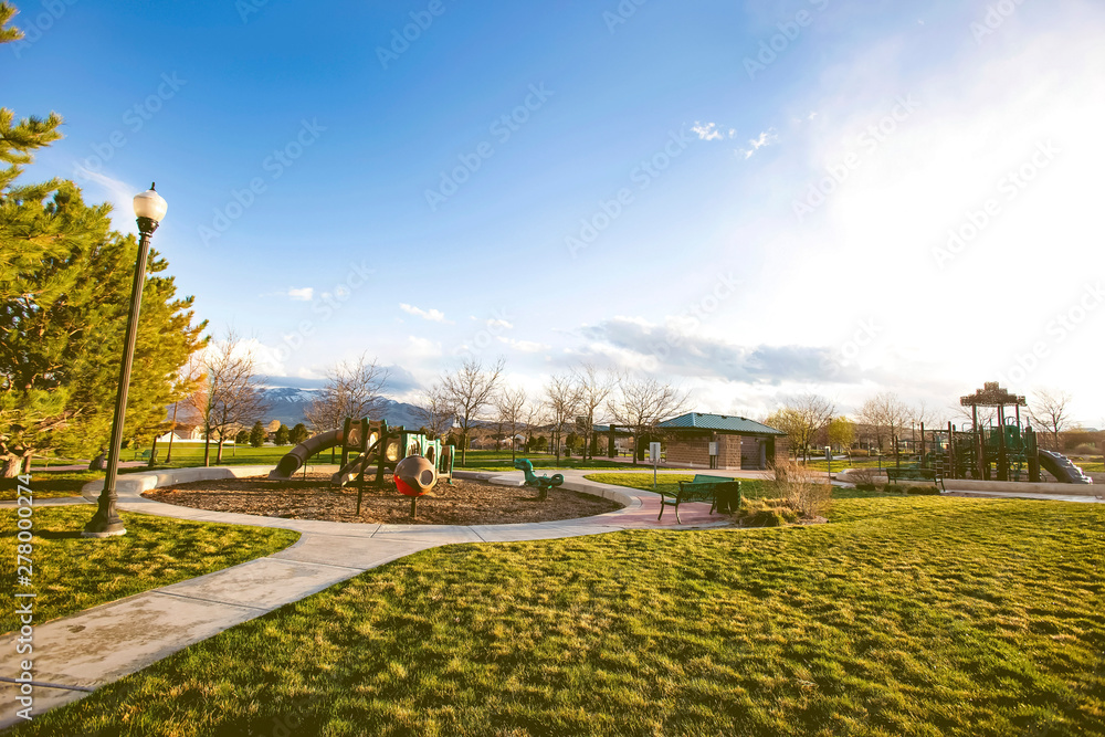 Park with playground restroom and pathways surrounded by vast grassy terrain