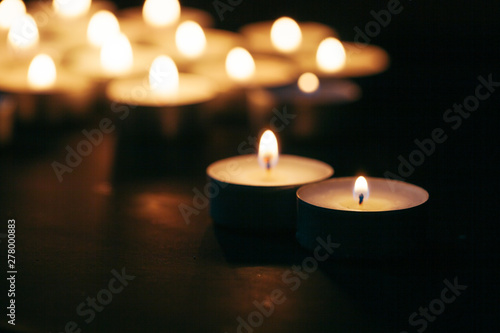 Many candles burning at night. Many candle flames glowing on dark background