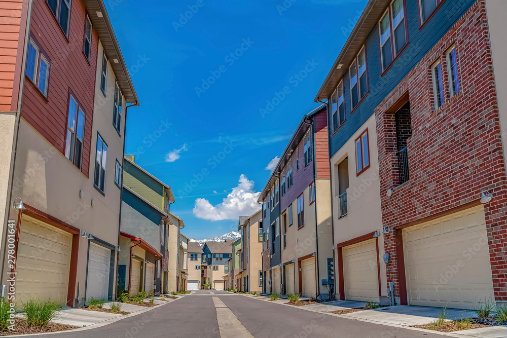 Rows of houses with paved road in the middle under blue sky on a sunny day