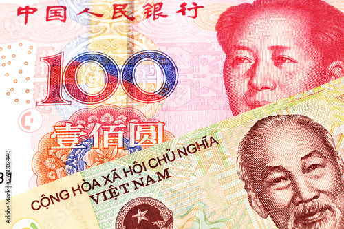 A colorful ten thousand dong note from Vietnam close up in macro with a red, Chinese one hundred yuan renminbi bank note