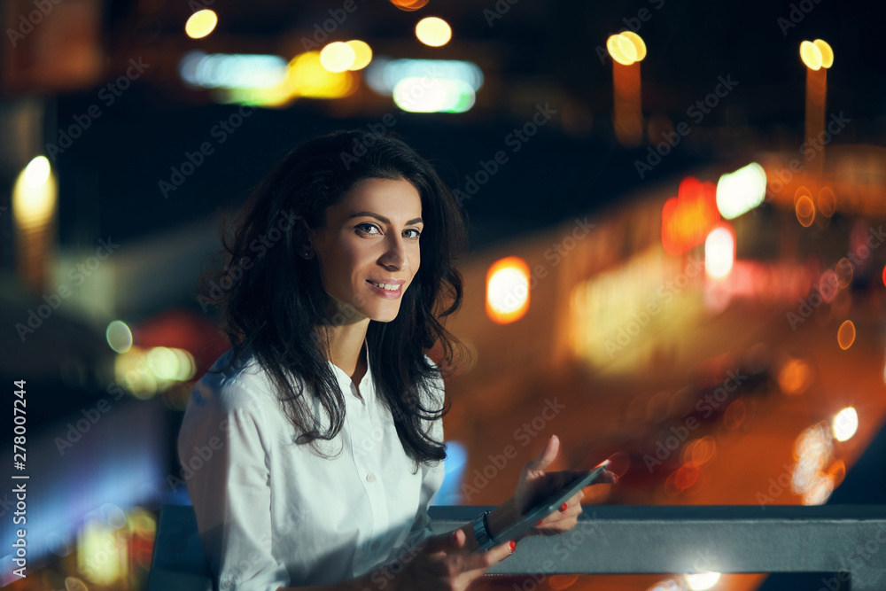 Woman over night cityscape holding a digital tablet texting Woman over night cityscape holding a digital tablet texting
