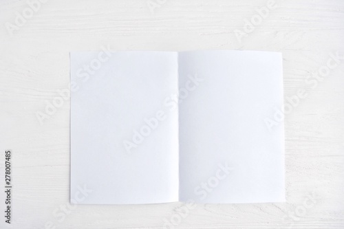 Blank sheet of white paper for design banner or card on textured neutral background, selective focus. Clear page with empty space for image or text on wooden white backdrop. Mockup concept  © Tetiana Ivanova