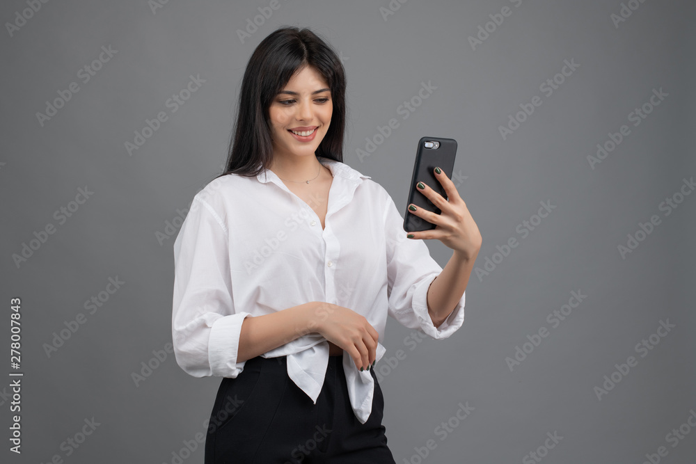 beautiful woman looking at her phone isolated over grey beautiful woman looking at her phone isolated over grey