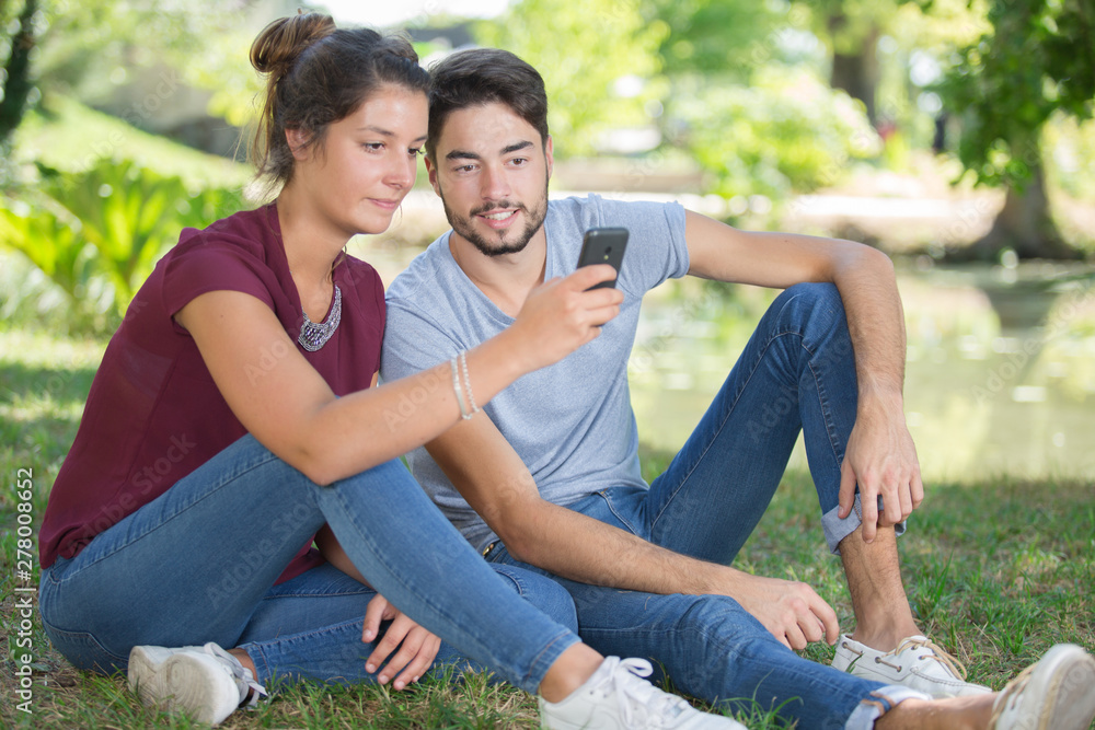 young couple using a mobile phone in the park young couple using a mobile phone in the park