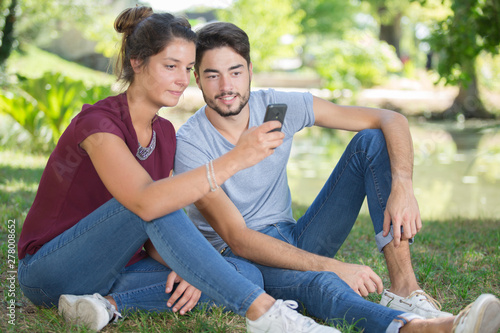 young couple using a mobile phone in the park