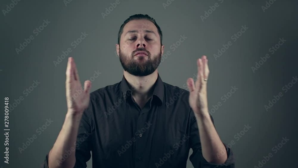 Beard man in shirt rising his open hands int he air and then putting his hands together in a prayer. Religion concept Beard man in shirt rising his open hands int he air and then putting his hands together in a prayer. Religion concept