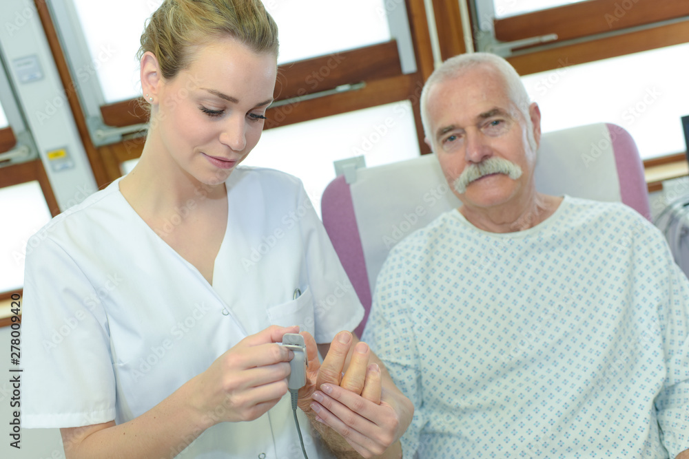 Fototapeta premium nurse putting pulse reader on to patients finger