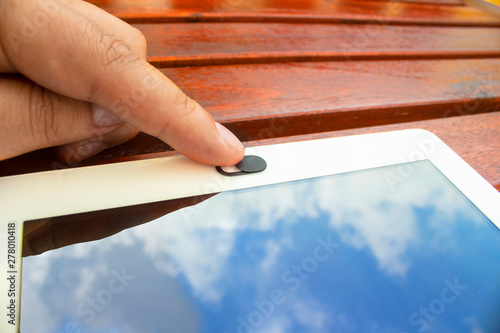 Finger sliding a selfie privacy cover for a table on a wooden table