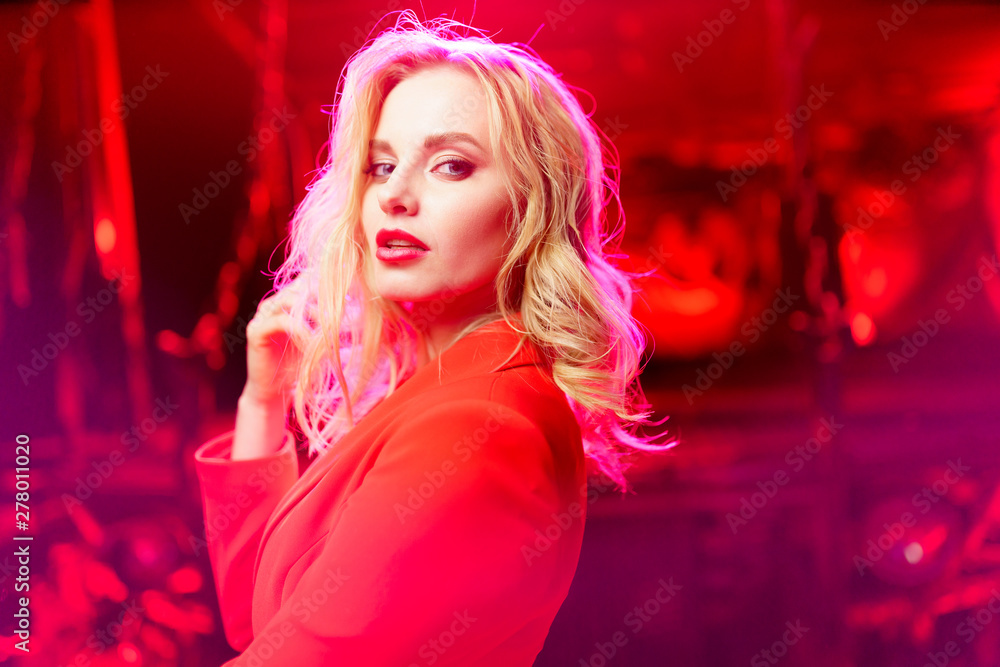 Photo of blonde in red jacket standing on red background Photo of blonde in red jacket standing on red background