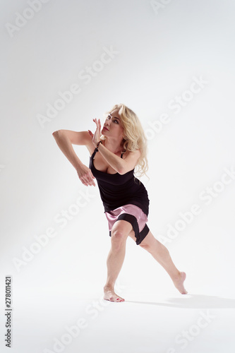 Side photo of long-haired blonde dancing in empty studio