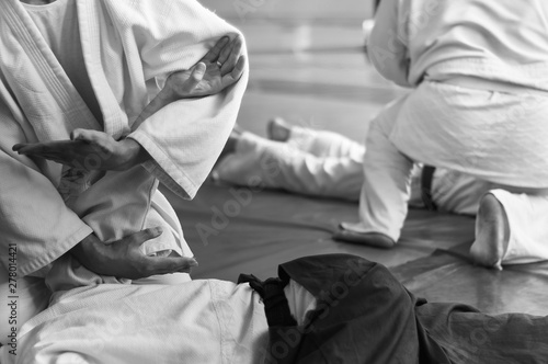 Black and white image of aikido. Hands of fighters. The traditional form of clothing in Aikido. Background image. No faces and recognizable elements © Uladzimir