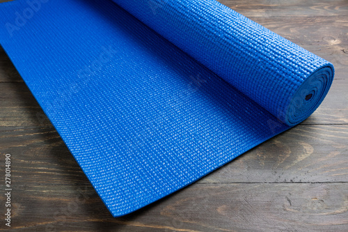 Blue yoga mat on wooden background. Equipment for yoga. Concept healthy lifestyle, sport and diet. Copy space