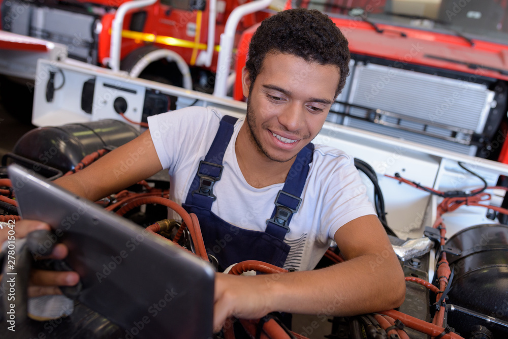 Naklejka premium mechanic with digital tablet while examining vehicule