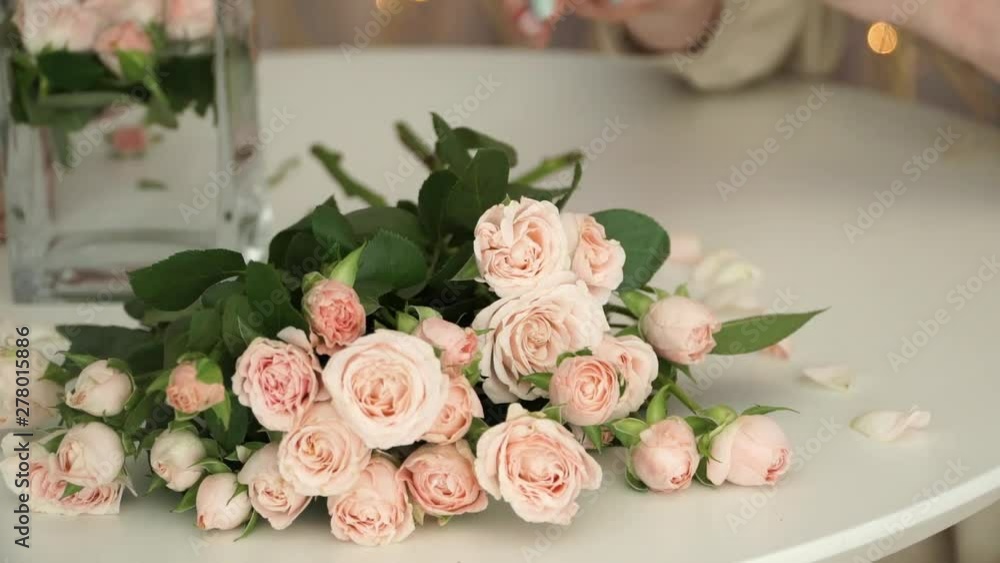 Female hands lay out fresh branches of bush tea roses on table. Florist prepares flowers for bouquet Female hands lay out fresh branches of bush tea roses on table. Florist prepares flowers for bouquet