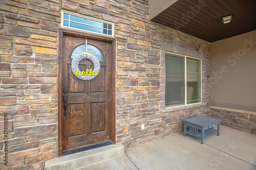 Facade of home with porch stone brick wall brown door and transom window