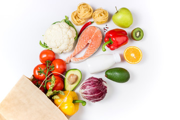 Healthy food background. Healthy food in paper bag fruits, vegetables, milk, pasta and fish on white background. Shopping food supermarket concept, meal and nutrition plan. Copy space