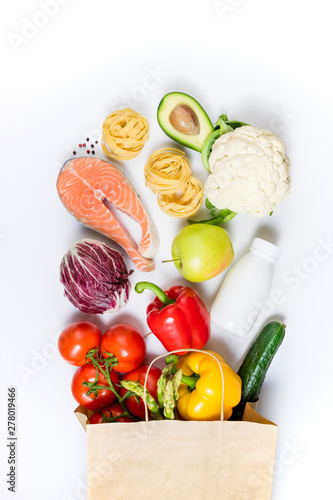 Fototapeta Naklejka Na Ścianę i Meble -  Healthy food background. Healthy food in paper bag fruits, vegetables, milk, pasta and fish on white background. Shopping food supermarket concept, meal and nutrition plan. Copy space