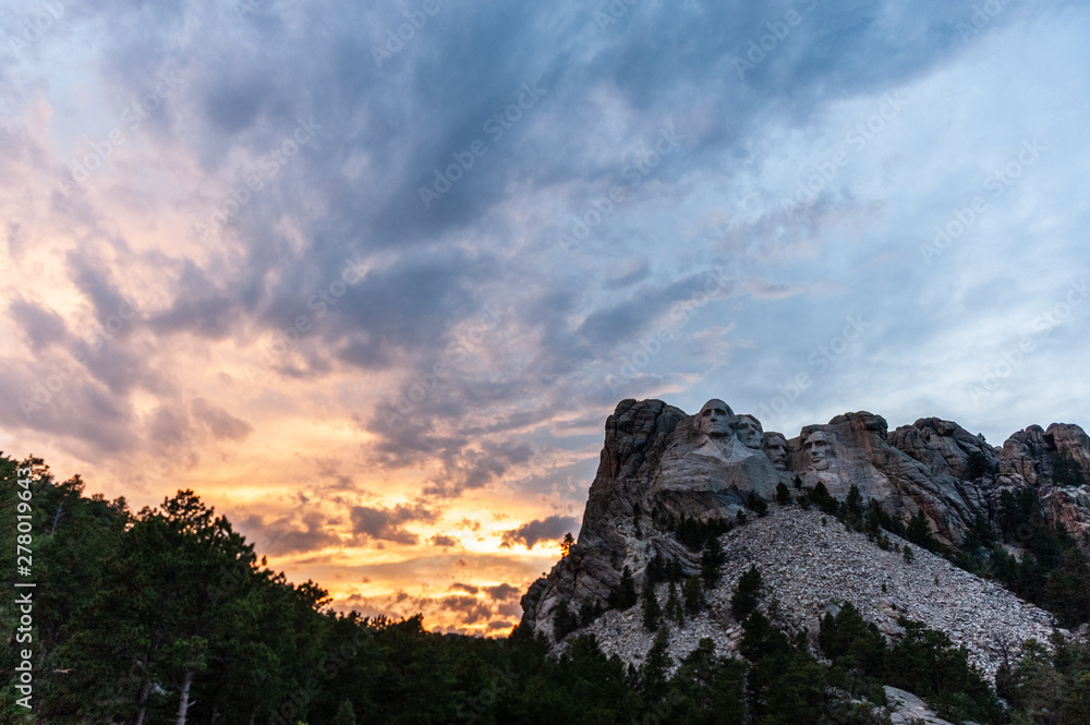 A dramatically colorful sky developing around sunset behind the four US presidents of Mount Rushmore, in North Dakota.