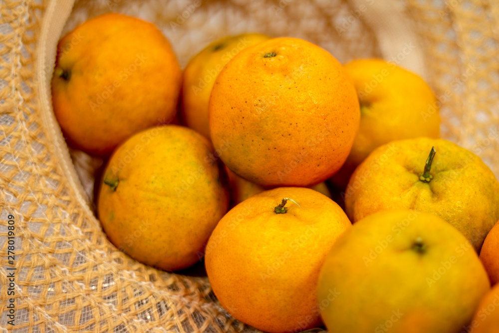 Tangerines served in female straw hat, on the table and white lace towel. Tangerines served in female straw hat, on the table and white lace towel.
