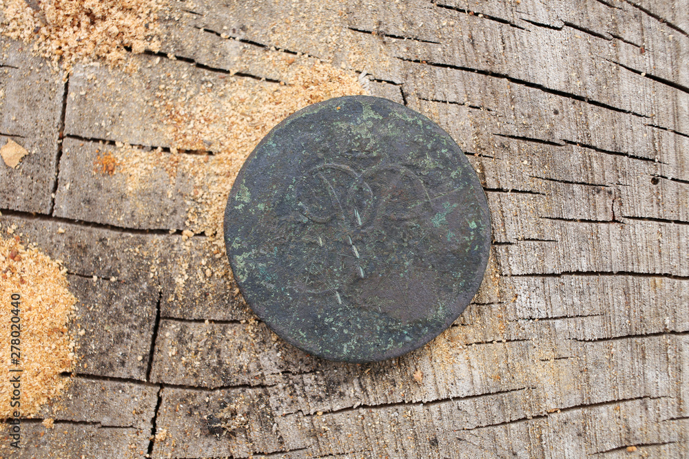 Ancient copper coin of Tsarist Russia in 1757, the Romanov dynasty, against the background of wood.