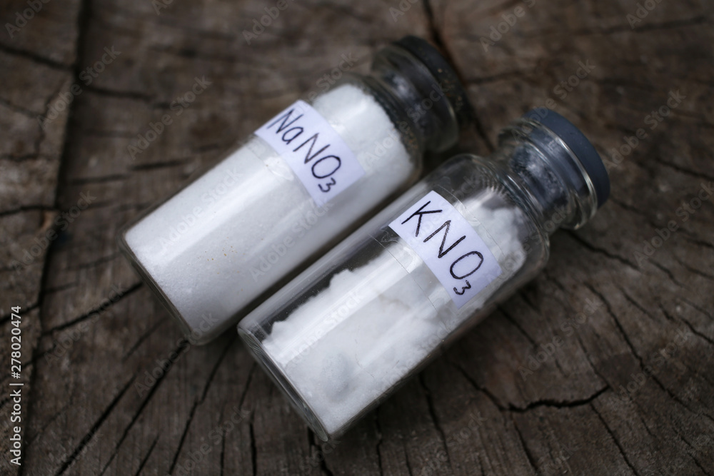 Φωτογραφία Salts of alkali metal nitrates, potassium nitrate and sodium nitrate in glass jars, on a dark wood background