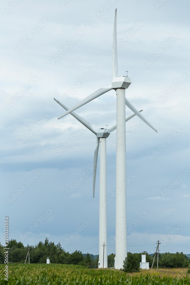 Pair of wind turbines against a sky with clouds. Clean energy for the agro farm.
