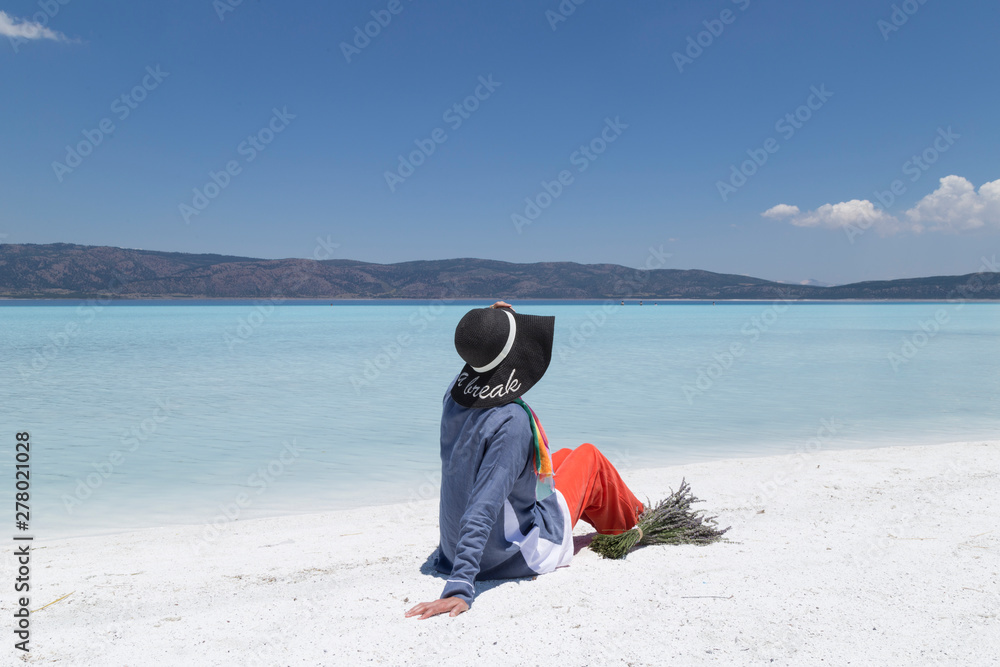 Φωτογραφία the beautiful girl hold lavender flowers lying and looking at the Salda lake from Turkey