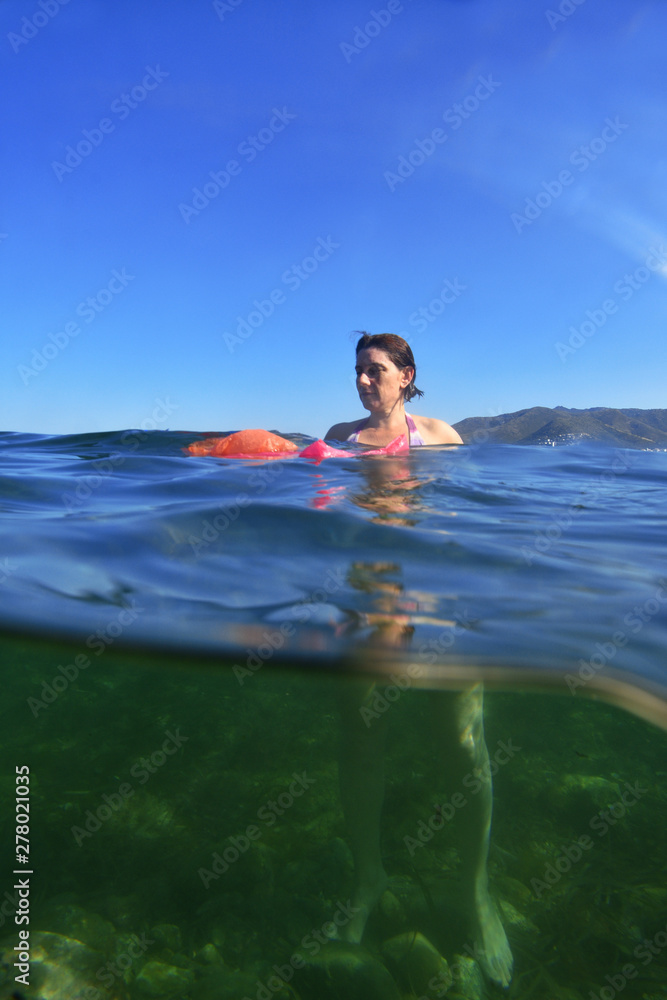 woman bathing in the sea with plastic in the water