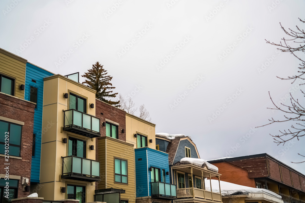 Residential buildings exterior with snowy roofs against cloudy sky in winter